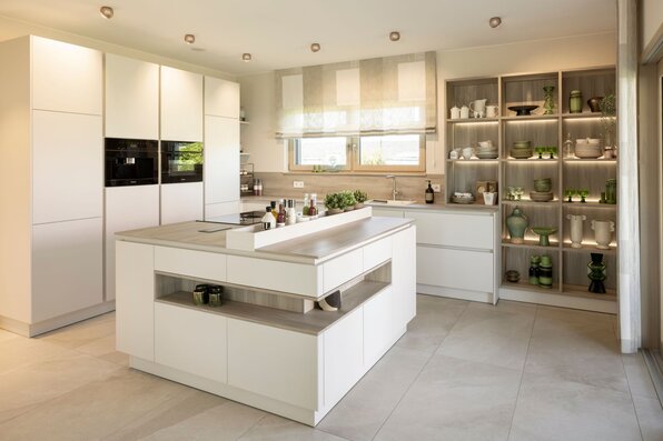 Moderne offene Küche im FingerHaus ARTIS 300 Musterhaus Nürnberg mit Kochinsel, Einbauschränken und stilvoller Beleuchtung.