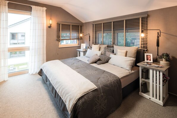 Modernes Schlafzimmer im FingerHaus-Musterhaus MEDLEY in Fellbach mit ruhiger Farbgestaltung, gemütlichem Bett, harmonischer Beleuchtung und klarer, zeitloser Raumaufteilung.