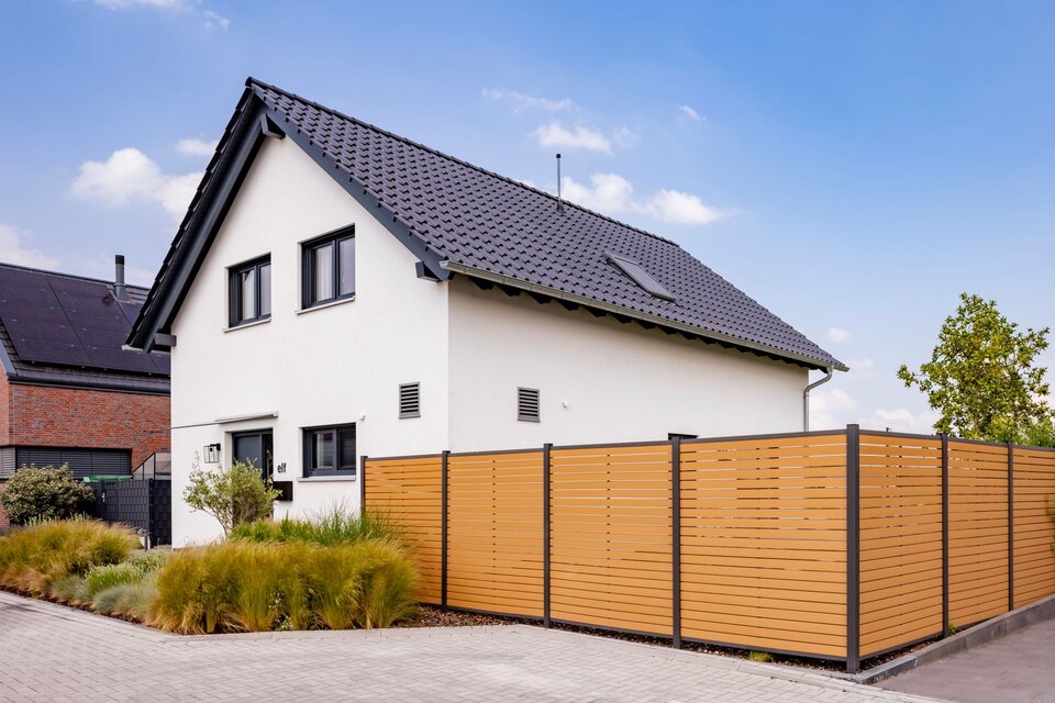 Frei geplantes FingerHaus mit moderner Außenansicht und seitlichem Sichtschutzzaun.