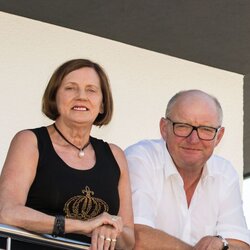 Vierköpfige Familie steht lächelnd auf dem Balkon eines modernen FingerHaus mit Flachdach und heller Fassade.