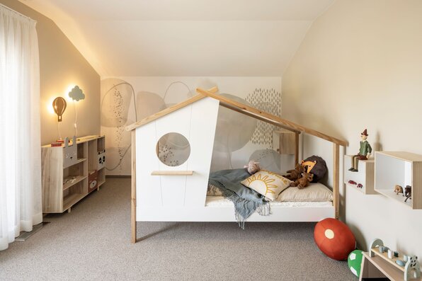 Kinderzimmer im FingerHaus ARTIS 300 Musterhaus Würzburg mit verspieltem Hausbett und liebevoller Dekoration.