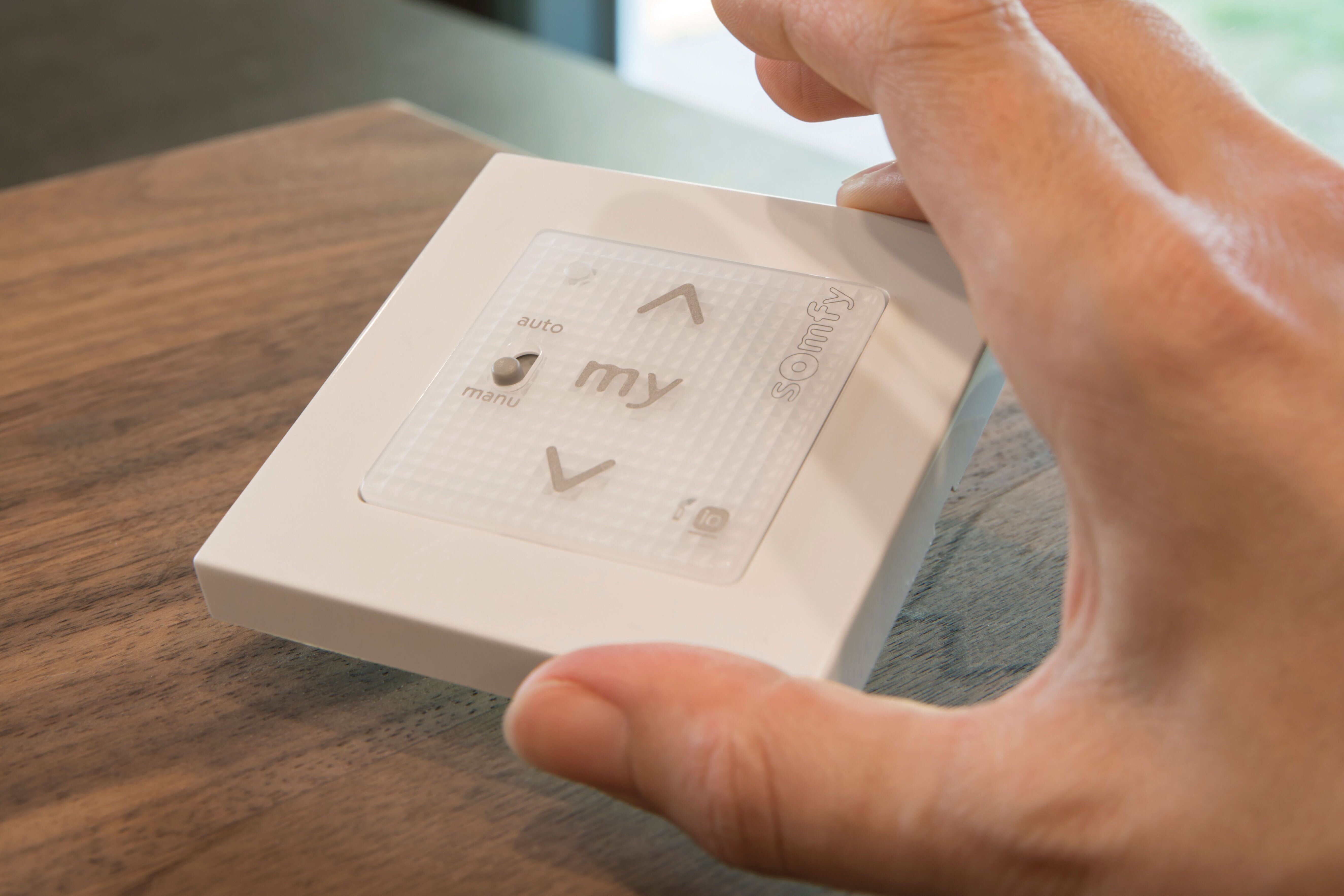 Hand betätigt moderne Steuerungseinheit für Jalousien im FingerHaus Musterhaus ALTERO in Gießen – Beispiel für intelligente Haustechnik.