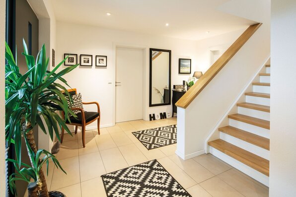 Heller Eingangsbereich mit Holztreppe, Pflanzen und moderner Dekoration in einem FingerHaus.