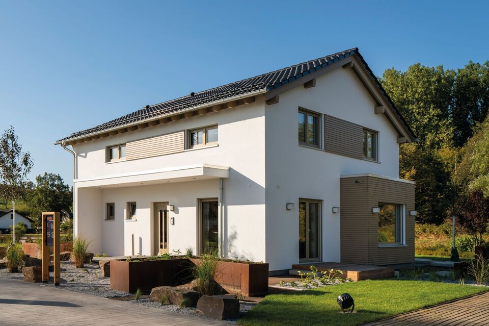 Moderne zweigeschossige Hausarchitektur mit Satteldach, heller Putzfassade, großen Fenstern und gepflegter Außenanlage im Musterhaus Frankenberg.