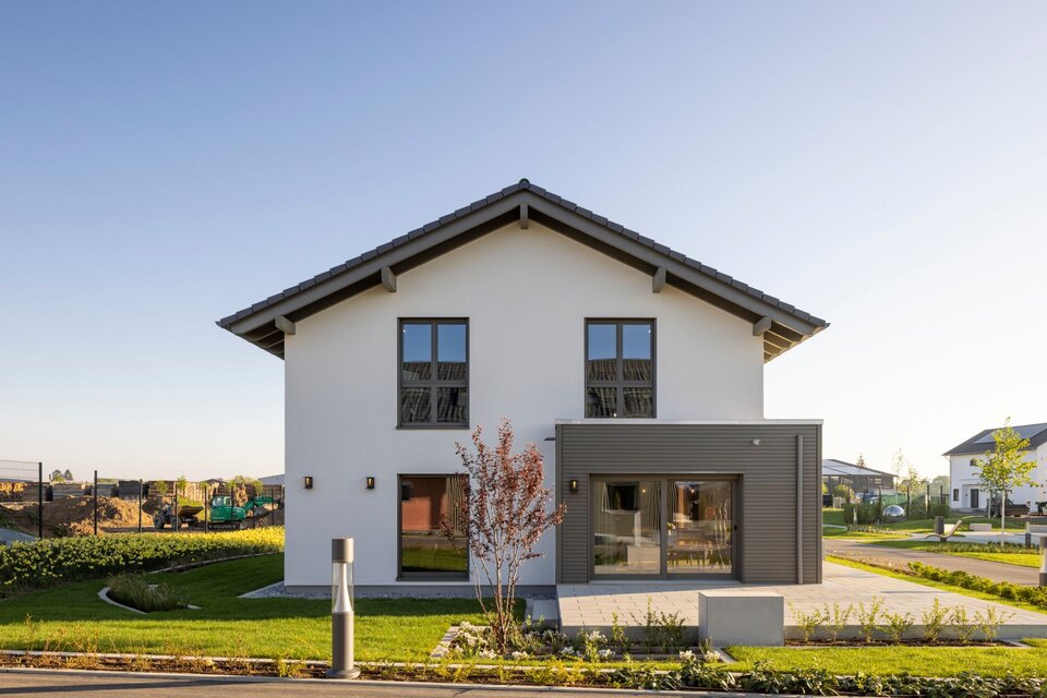 FingerHaus ARTIS 400 Musterhaus im Schwarzwald mit Satteldach, weißer Fassade, symmetrischen Fenstern und modernem Erker mit Holz-Elementen.