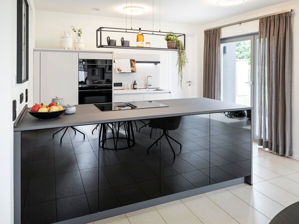 Moderne Küche im frei geplanten FingerHaus Musterhaus Marburg mit Kücheninsel, Einbaugeräten und stilvoller Beleuchtung.