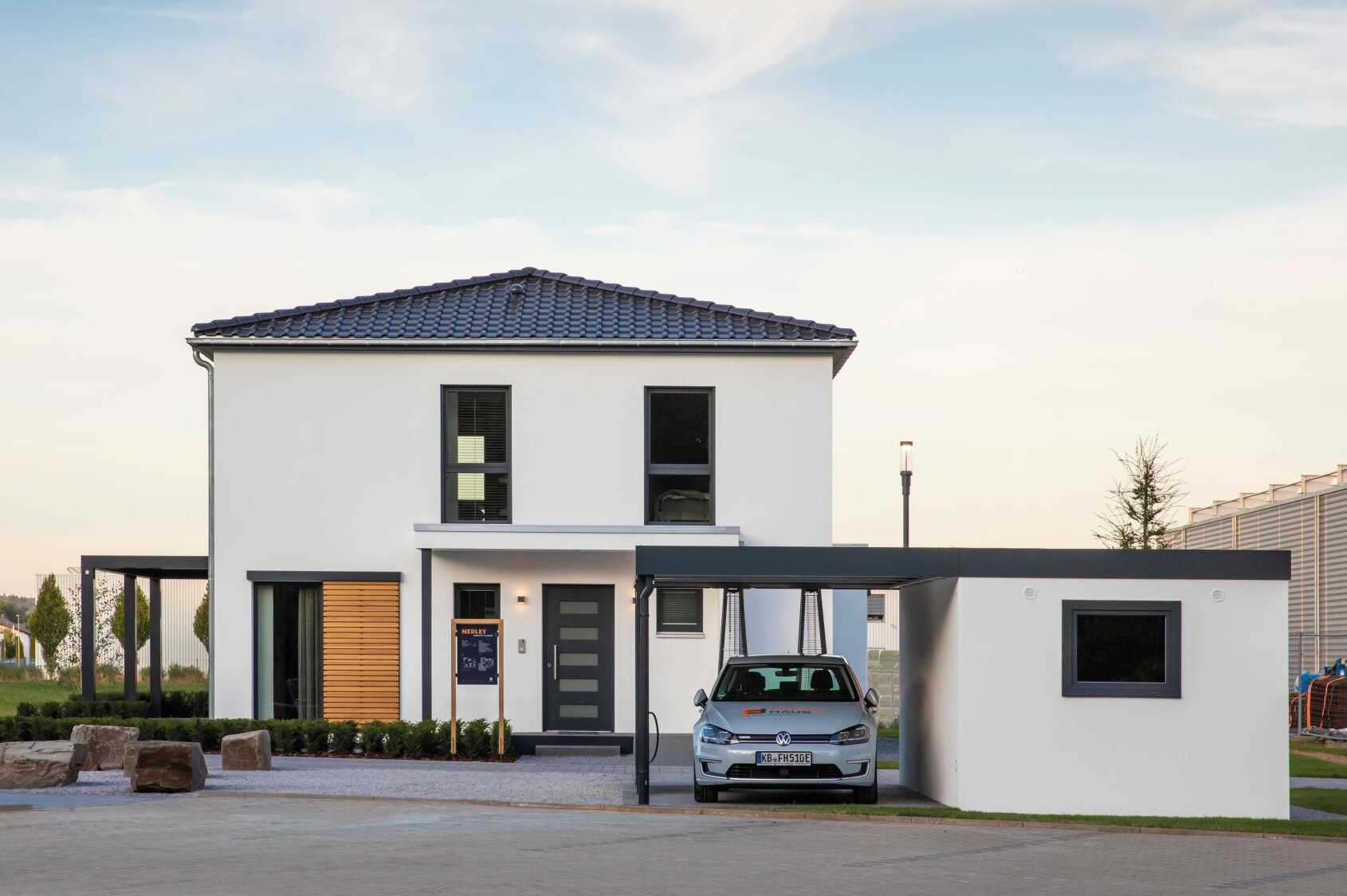 Moderne Außenansicht des FingerHaus Musterhauses MEDLEY 300 B in Frankenberg mit weißer Fassade, Walmdach, Carport und klarer Architektur.