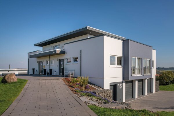 Modernes, frei geplantes FingerHaus mit Flachdach und Einliegerwohnung, großer Einfahrt, drei Garagen und klarer Architektur.