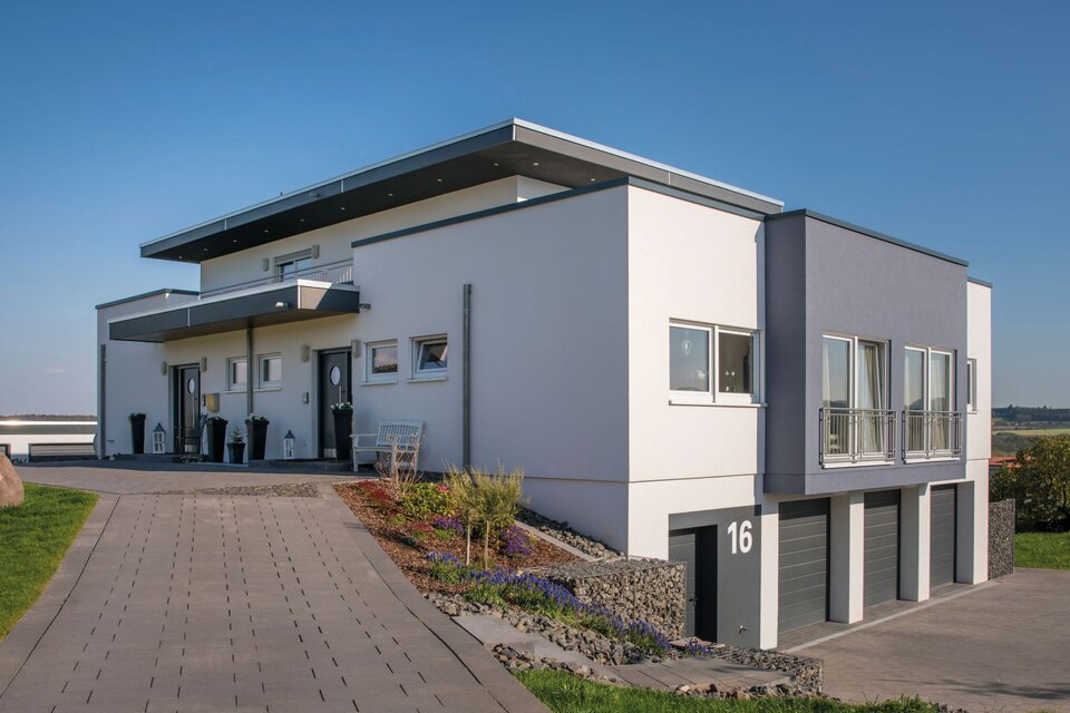 Modernes, frei geplantes FingerHaus mit Flachdach und Einliegerwohnung, großer Einfahrt, drei Garagen und klarer Architektur.