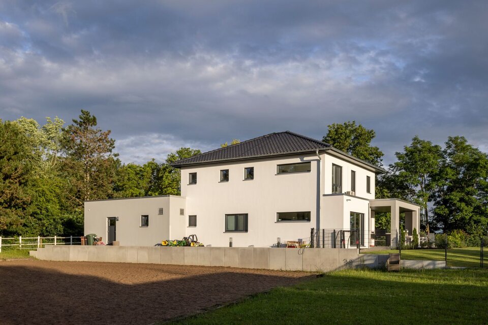 Großzügiges, modernes FingerHaus mit Flachdach-Elementen und angrenzendem Außenbereich, eingebettet in grüne Natur.