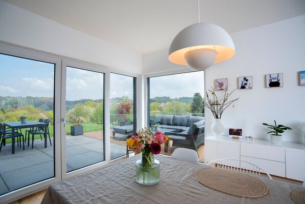 Esszimmer in einem frei geplanten FingerHaus mit Blick auf die Terrasse und große Glasfronten, die den Raum mit Tageslicht füllen.
