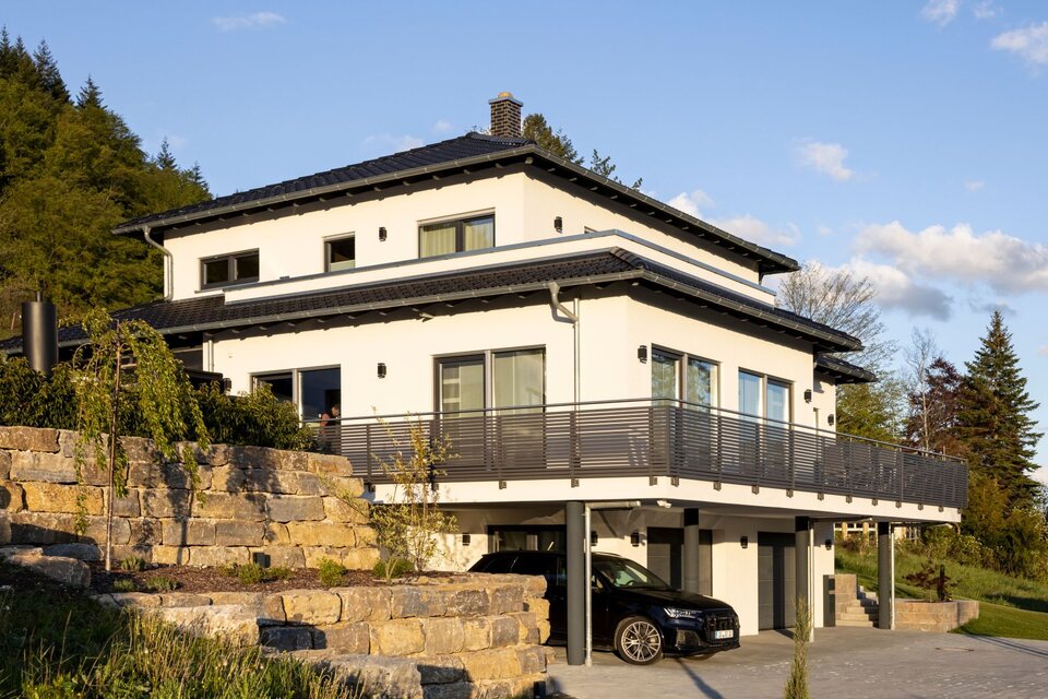 Großzügiges frei geplantes Architektenhaus von FingerHaus mit umlaufendem Balkon, moderner Fassade und integrierter Garage im Hanggrundstück.