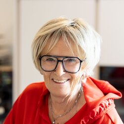 Porträt einer Seniorin im Wohnzimmer des Kundenhauses NIVO 80 vor einem Kamin.