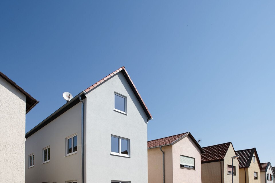 Reihe moderner, schmaler Stadthäuser mit Satteldach unter blauem Himmel, gebaut von FingerHaus.