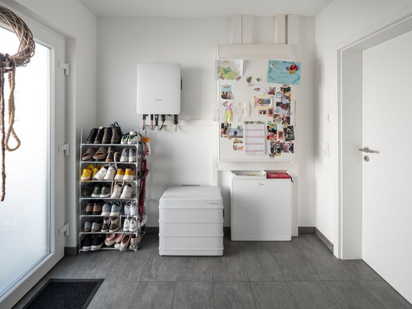 Hauswirtschaftsraum des Kundenhauses NIVO 80 mit Wechselrichter, Batteriespeicher, Technikschrank und Schuhregal.