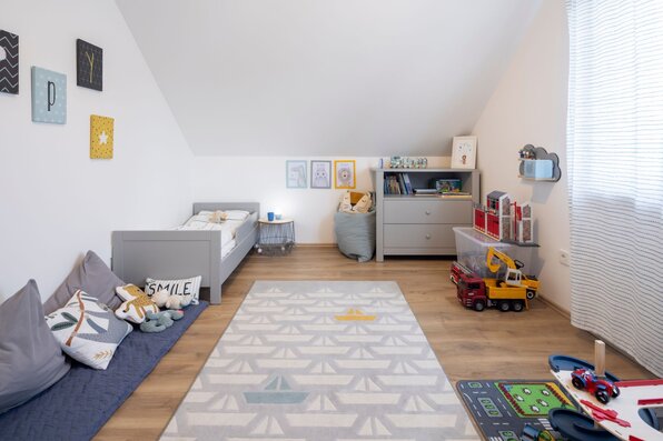 Kinderzimmer im SENTO 403 mit Einzelbett, Spielteppich, Kommode, Sitzsack und Spielzeug unter einer Dachschräge