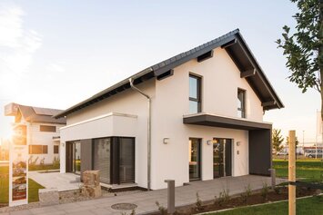 FingerHaus-Musterhaus NEO in Günzburg bei Abendsonne, modernes Einfamilienhaus mit Satteldach, Erker und gepflegtem Vorgarten im Musterhauspark.