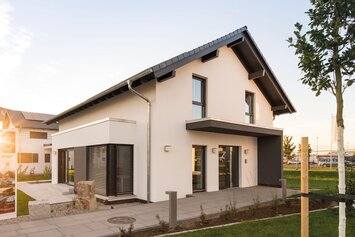 FingerHaus-Musterhaus NEO in Günzburg bei Abendsonne, modernes Einfamilienhaus mit Satteldach, Erker und gepflegtem Vorgarten im Musterhauspark.