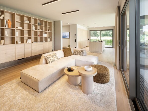 Wohnbereich im FingerHaus Musterhaus NIVO in Frankenberg mit Ecksofa, großer Regalwand, bodentiefer Glasfront und offener Küche.