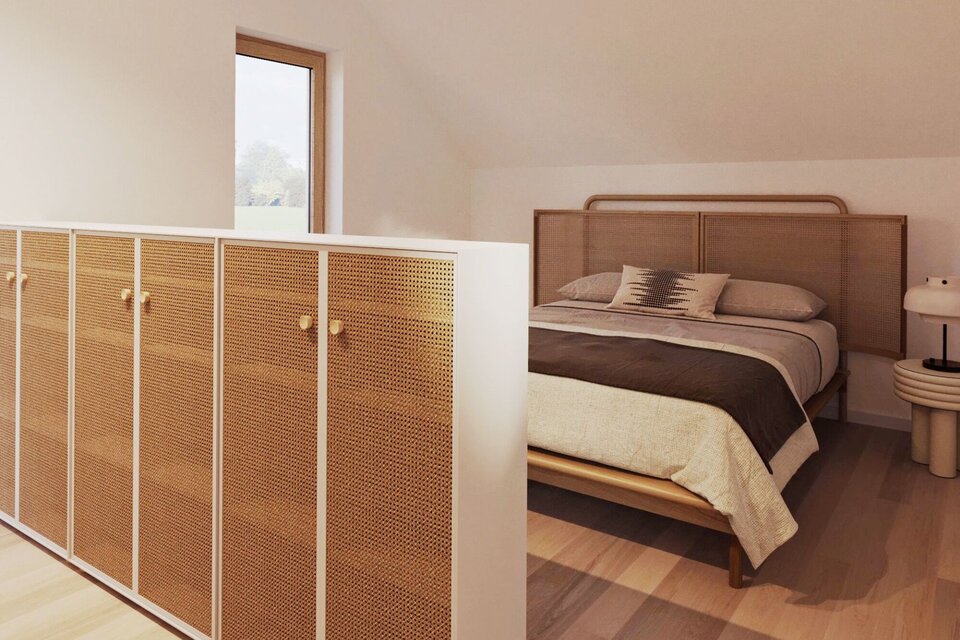 Gemütliches Schlafzimmer im Dachgeschoss mit Holzboden, großem Bett und geflochtenem Sideboard.