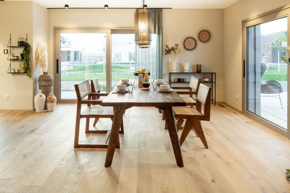 Essbereich im FingerHaus ARTIS 400 Musterhaus Schwarzwald mit großem Holztisch, modernen Stühlen, dekorativen Elementen und viel Tageslicht durch große Fensterfronten.