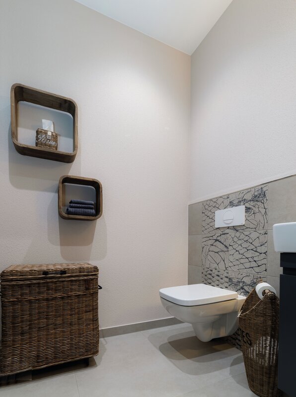 Modernes Gäste-WC mit Wand-WC, dekorativen Fliesen und stilvollen Ablagen im Musterhaus MEDLEY 300 B in Poing.