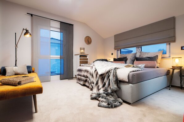 Gemütliches Schlafzimmer mit Doppelbett, moderner Beleuchtung und stilvollem Interieur im Musterhaus MEDLEY 300 B in Poing.
