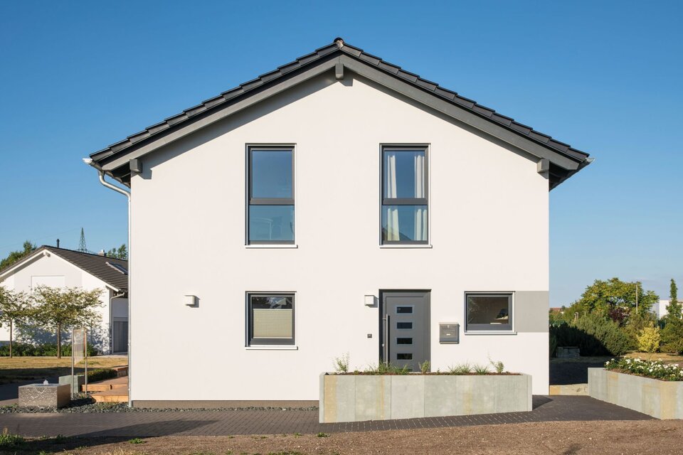 Frontansicht des Musterhauses UNO 2.0 in Leipzig mit klarer Linienführung, grauen Fensterrahmen und moderner Haustür.