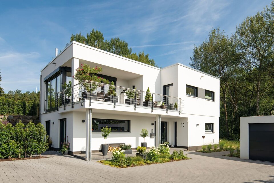 Modernes FingerHaus im Bauhausstil mit Flachdach, klaren Linien, großem Balkon, bodentiefen Fenstern und separater Garage, umgeben von Garten und Einfahrt.
