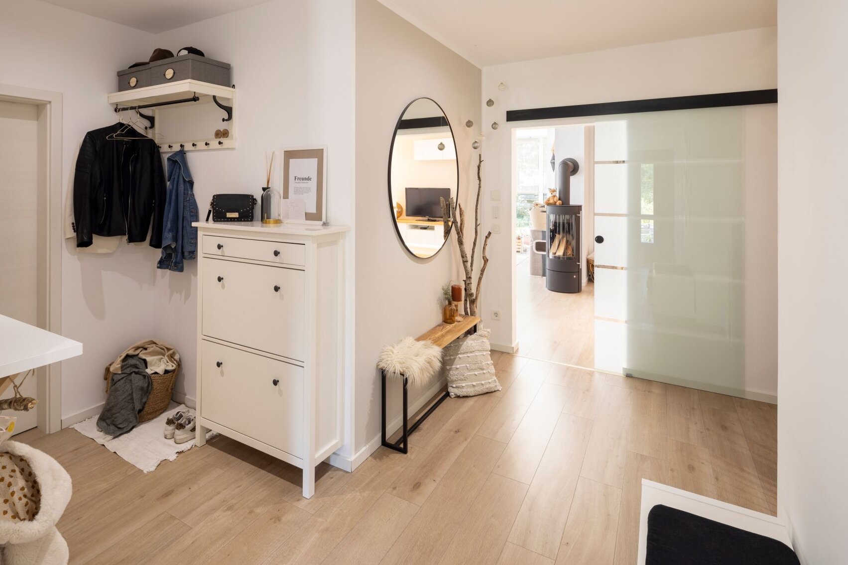 Moderner Eingangsbereich in einem frei geplanten FingerHaus mit Garderobe, Spiegel und stilvollen Möbeln.