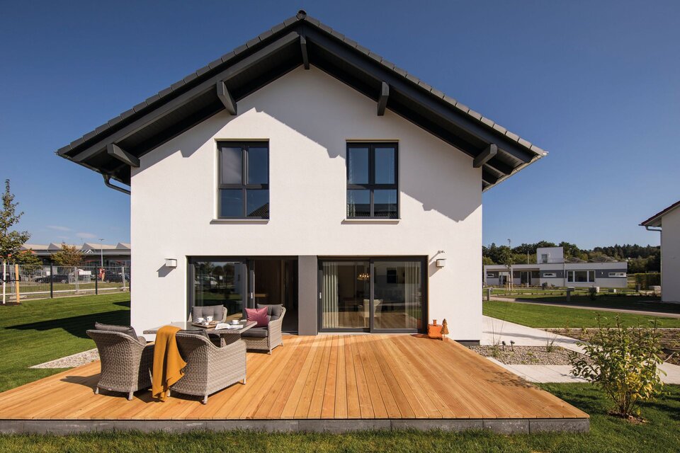 Große Terrasse mit gemütlicher Sitzgruppe am FingerHaus NEO Musterhaus in Günzburg, direkt angrenzend an die moderne Fassade.