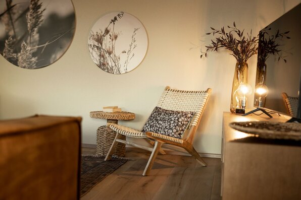 Gemütliche Sitzecke im FingerHaus ARTIS 400 Musterhaus Schwarzwald mit Korbsessel, Beistelltisch, stimmungsvoller Beleuchtung und Wanddeko.