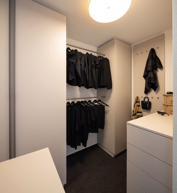 Begehbare Ankleide im Musterhaus TALO Fulda mit Kleiderstangen, Schubladen und praktischer Stauraumlösung in modernem Design.