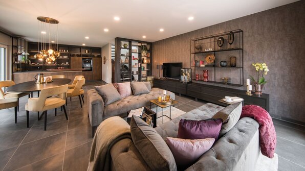 Wohnbereich im Musterhaus MEDLEY 300 B in Kassel mit offener Gestaltung, eleganten Sofas, modernem Essbereich und stilvollem Regal.