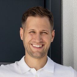 Eine vierköpfige Familie steht vor dem Eingang ihres frei geplanten FingerHaus mit moderner grauer Haustür und heller Fassade.