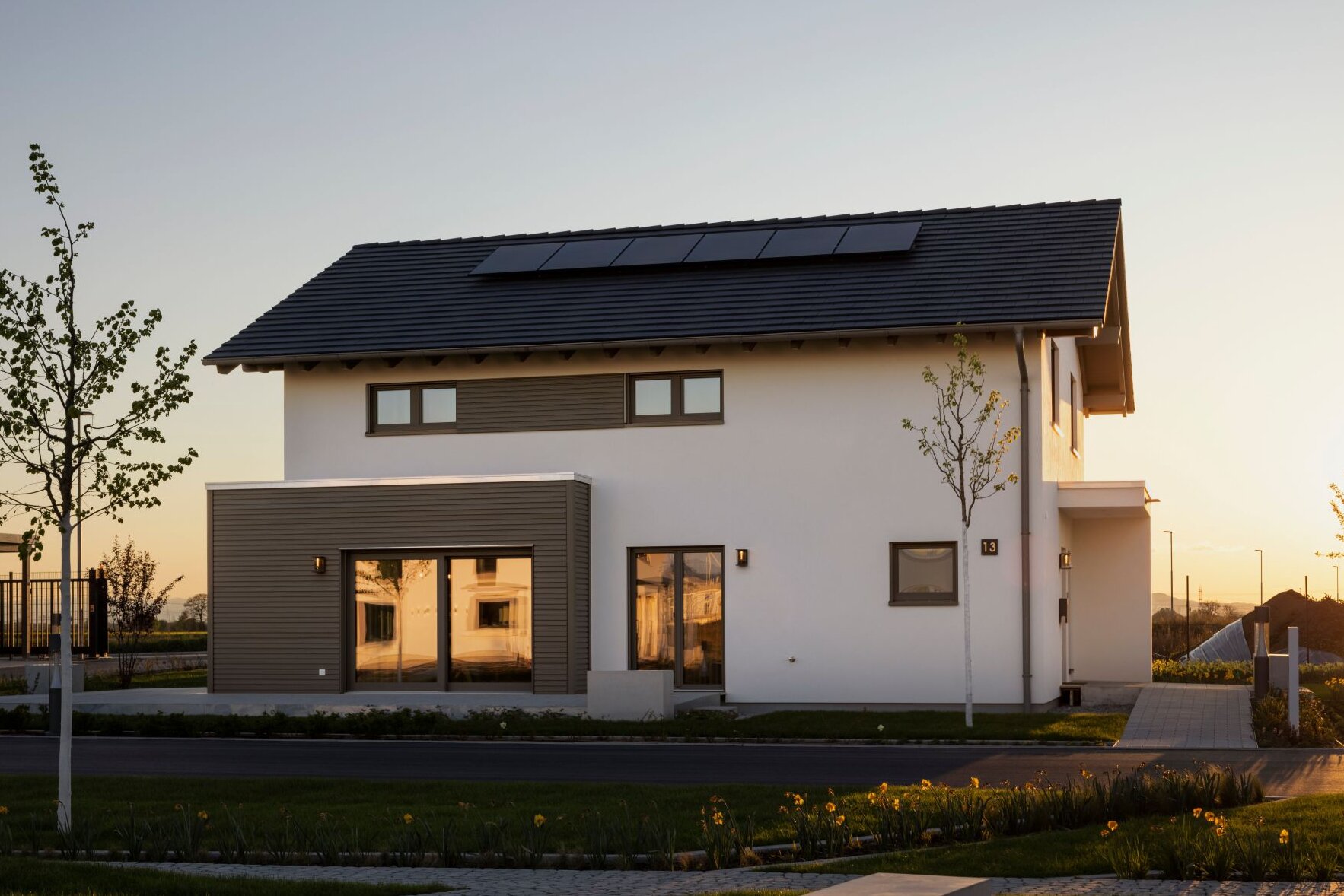 FingerHaus ARTIS 400 Musterhaus im Schwarzwald bei Sonnenuntergang mit Satteldach, Photovoltaikanlage, klarer Architektur und modernen Holz-Elementen.