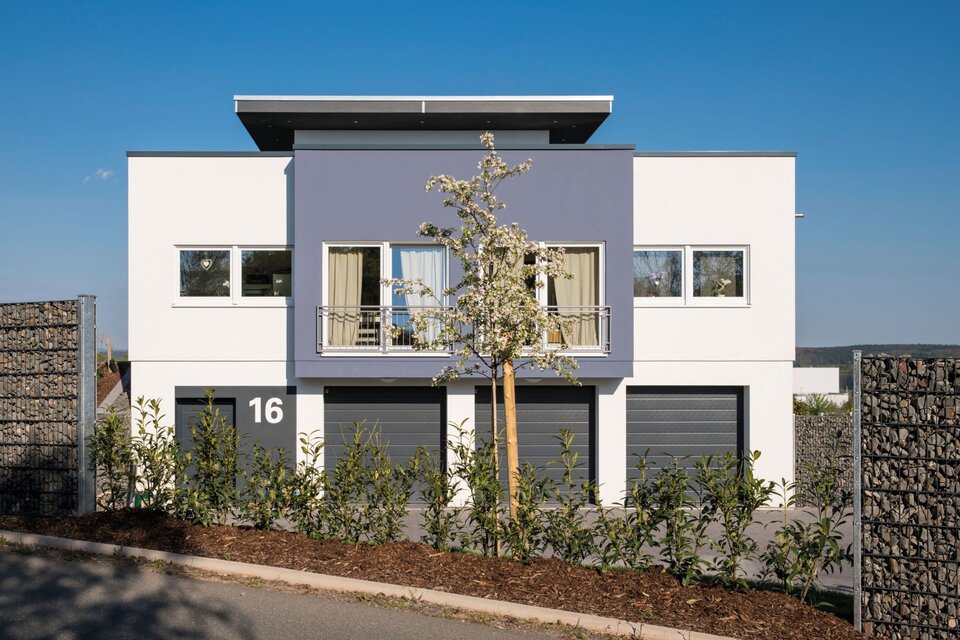 Frei geplantes FingerHaus mit moderner Fassade, drei Garagen und klarer Linienführung, aufgenommen von der Straßenseite.