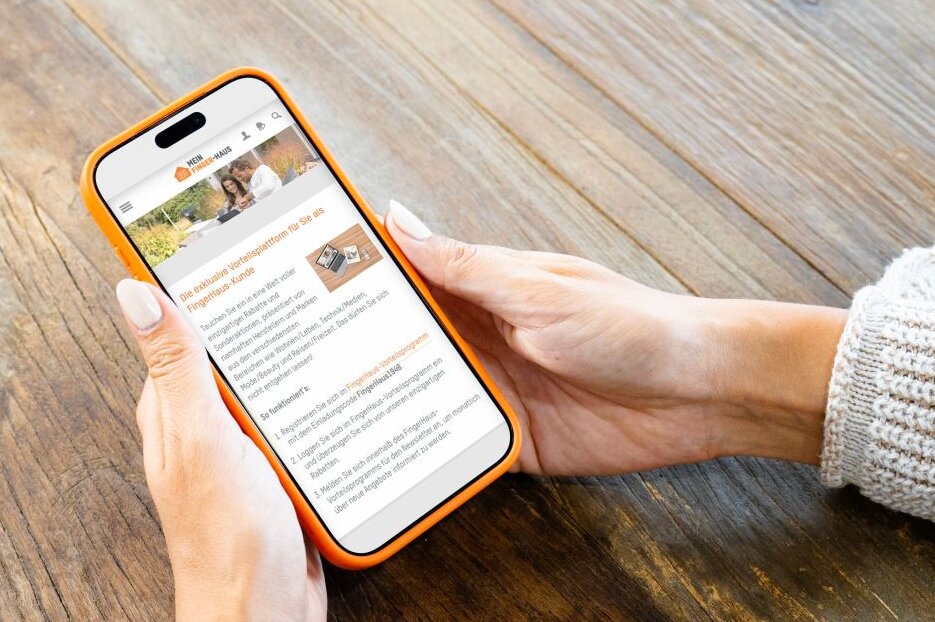 Person hält ein Smartphone mit dem FingerHaus Serviceportal in den Händen. Auf dem Display sind Informationen zum Kundenvorteilsprogramm dargestellt.