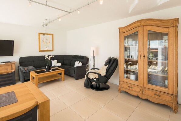 Wohnzimmer in einem frei geplanten FingerHaus mit heller Einrichtung, gemütlicher Sitzecke und klassischem Holzschrank.