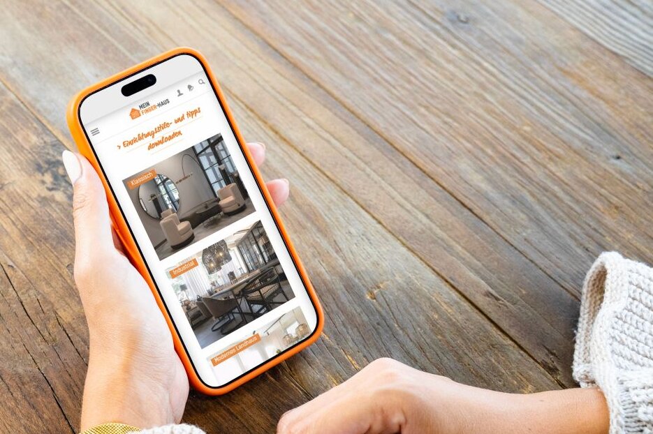 Person hält ein Smartphone mit dem FingerHaus Serviceportal in den Händen. Auf dem Display sind Informationen zum FingerLoft dargestellt.