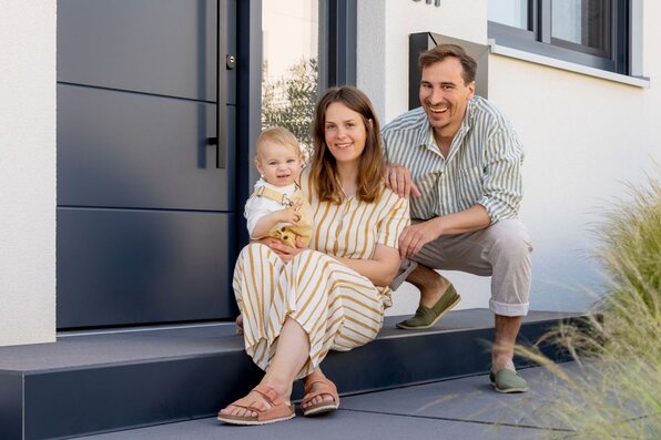 Frei geplantes FingerHaus mit modernem Eingangsbereich und Familie davor.