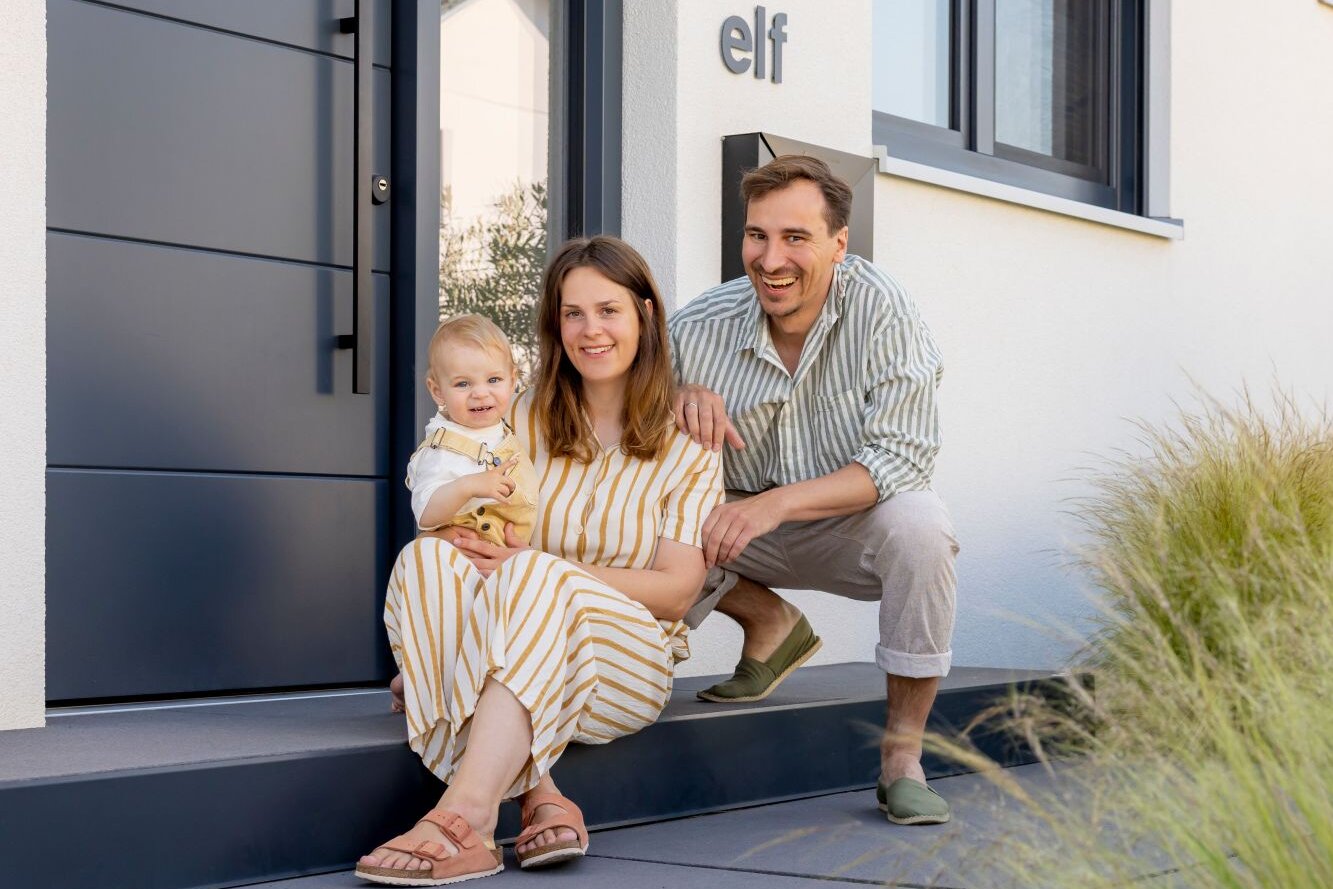 Frei geplantes FingerHaus mit modernem Eingangsbereich und Familie davor.