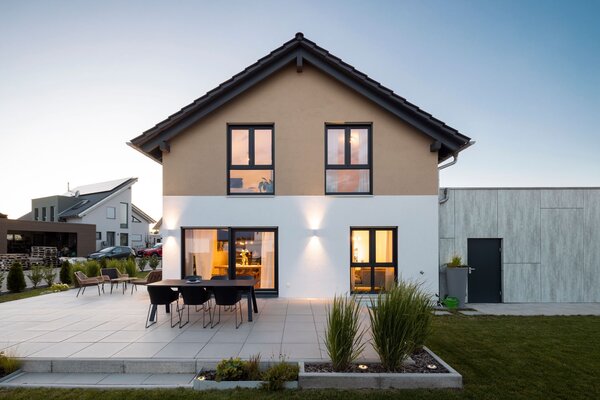 Finger-Haus NEO 211 mit Terrasse und beleuchtetem Wohnbereich in der Dämmerung.