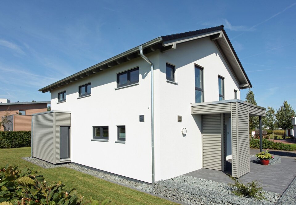 Außenansicht des FingerHaus Musterhauses NEO 300 in Hannover mit heller Fassade, Satteldach, moderner Eingangsüberdachung und klarer Architektur.