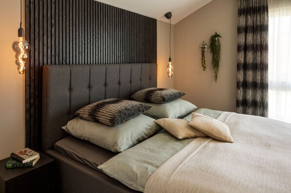 Gemütliches Schlafzimmer im FingerHaus ARTIS 300 Musterhaus Nürnberg mit modernem Bettdesign und Akzentwand.