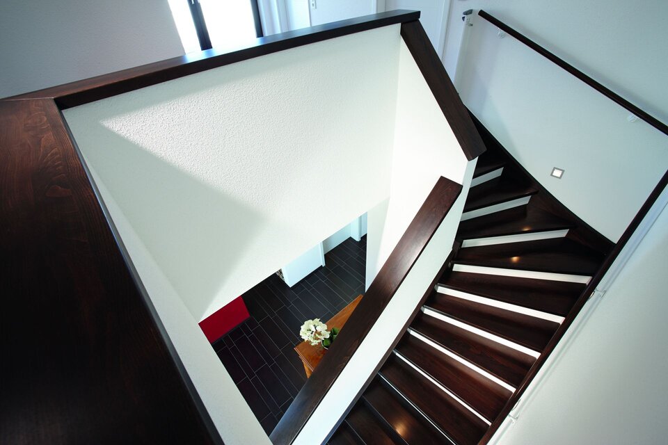 Moderne Holztreppe mit dunklen Stufen und hellem Treppenhaus.