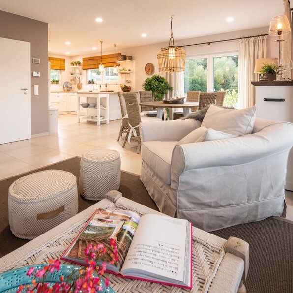 Helles und gemütliches Wohnzimmer im FingerHaus Musterhaus JUNO 402 in Frankenberg mit offener Wohnküche, modernem Essbereich, hellen Möbeln und stilvoller Dekoration.