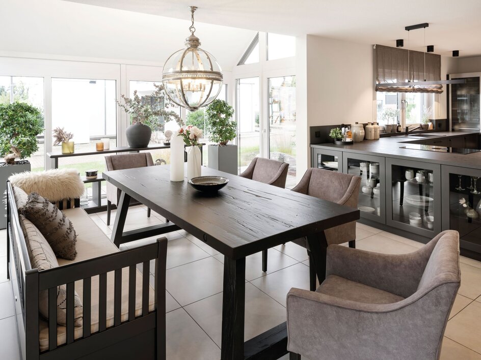 Moderne Küche im FingerHaus-Musterhaus NEO in Wuppertal mit großzügigem Esstisch, offenen Übergängen zum Wohnbereich, großen Fensterflächen, Kücheninsel und stilvoller Beleuchtung.