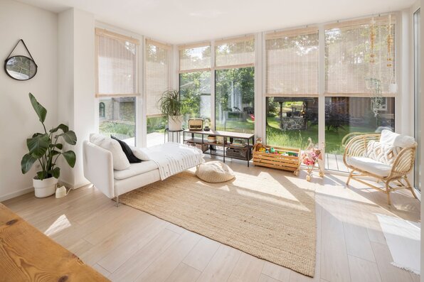Wintergarten im frei geplanten FingerHaus mit großen Panoramafenstern, gemütlicher Einrichtung und Blick ins Grüne.