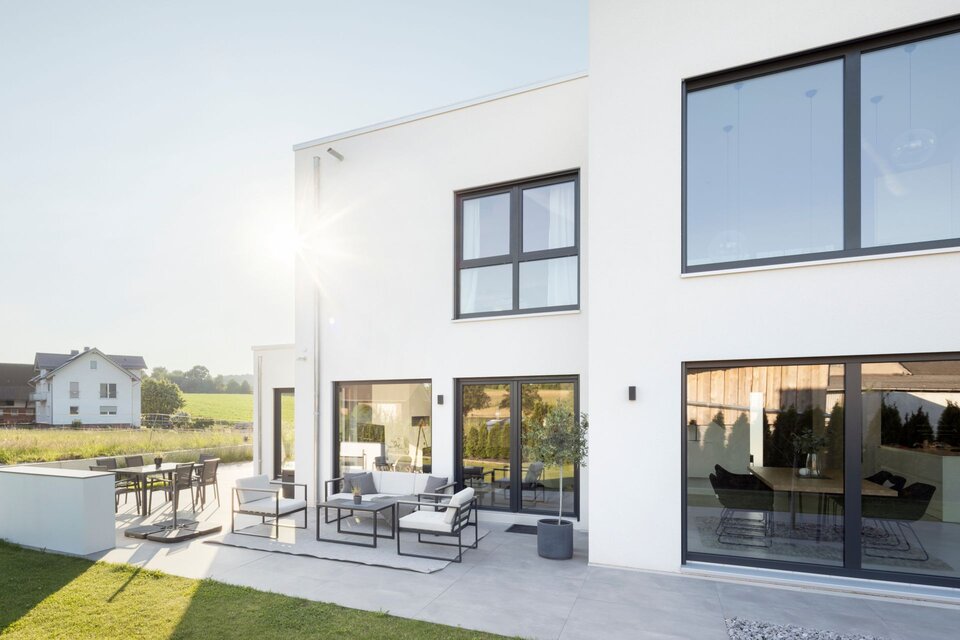 Moderne Terrasse eines frei geplanten FingerHaus im Bauhaus-Stil mit Sitz- und Essbereich. Große Fensterfronten sorgen für lichtdurchflutete Innenräume.